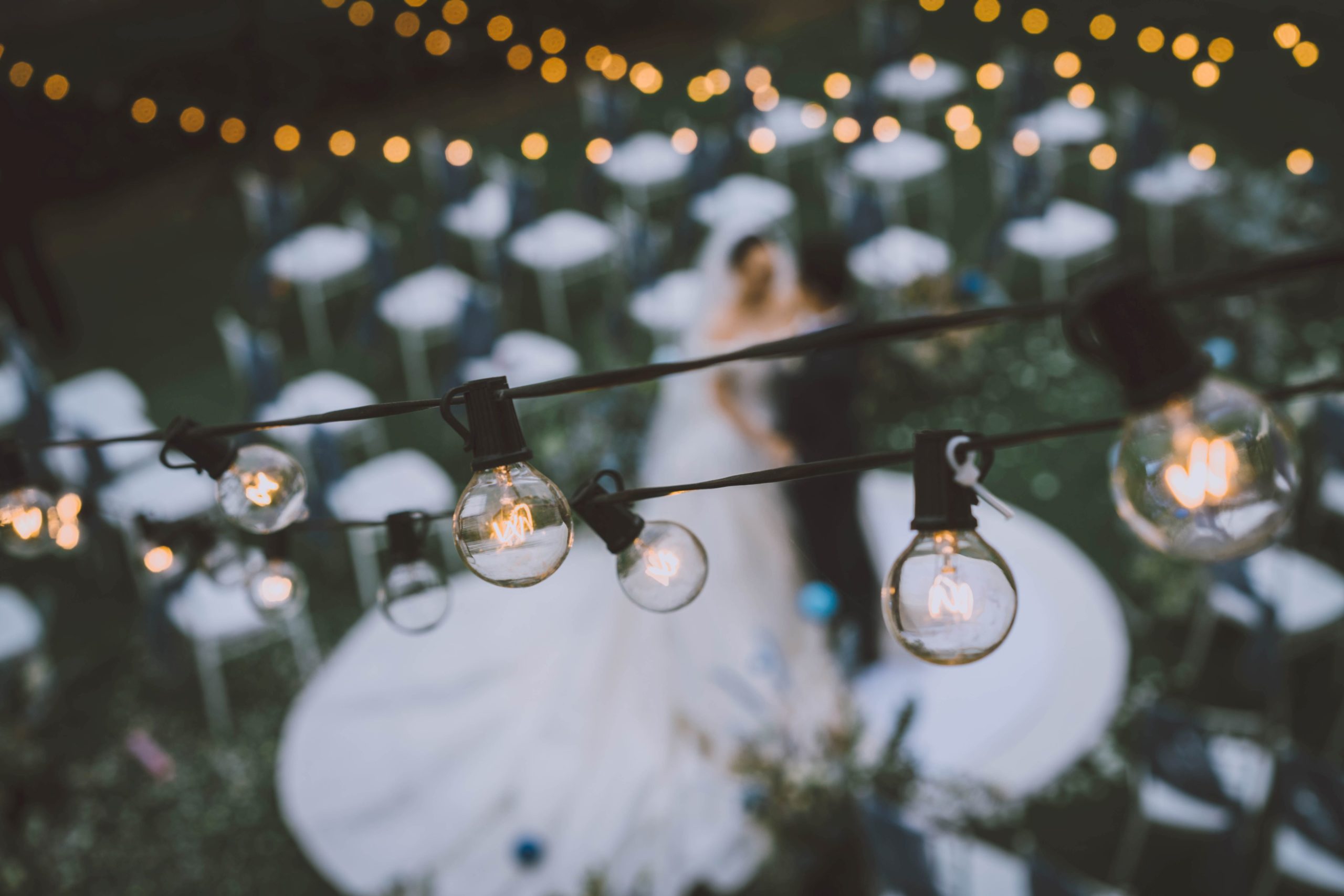Edison bulb string light wedding supplies outside with bride and groom