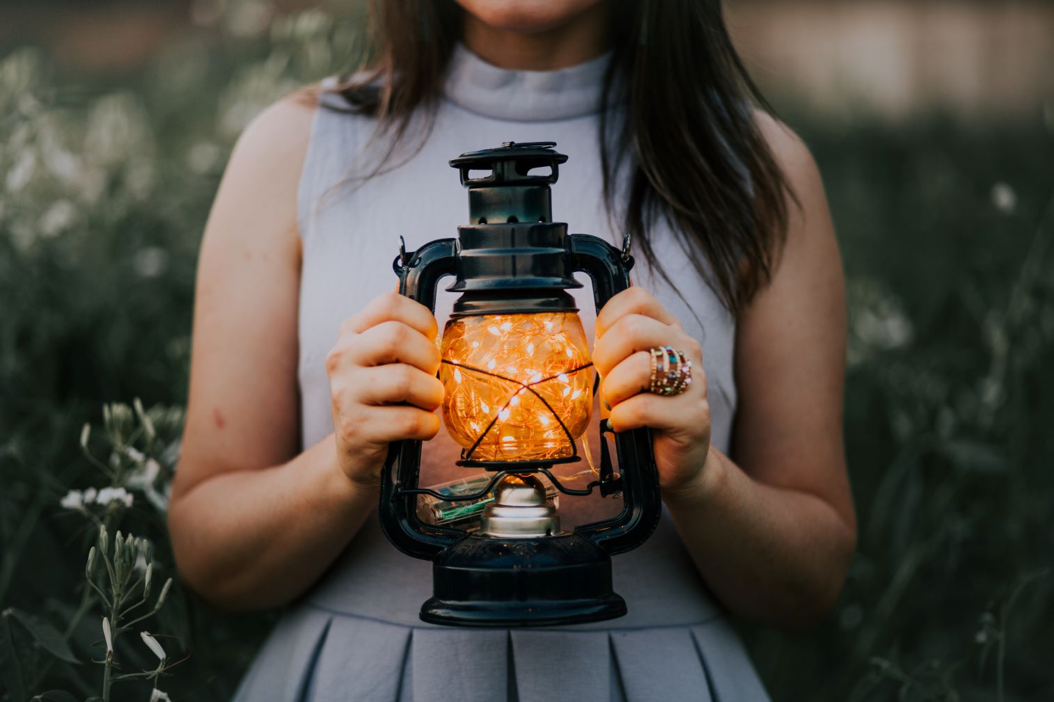 Woman holding a lantern filled with fairy lights.