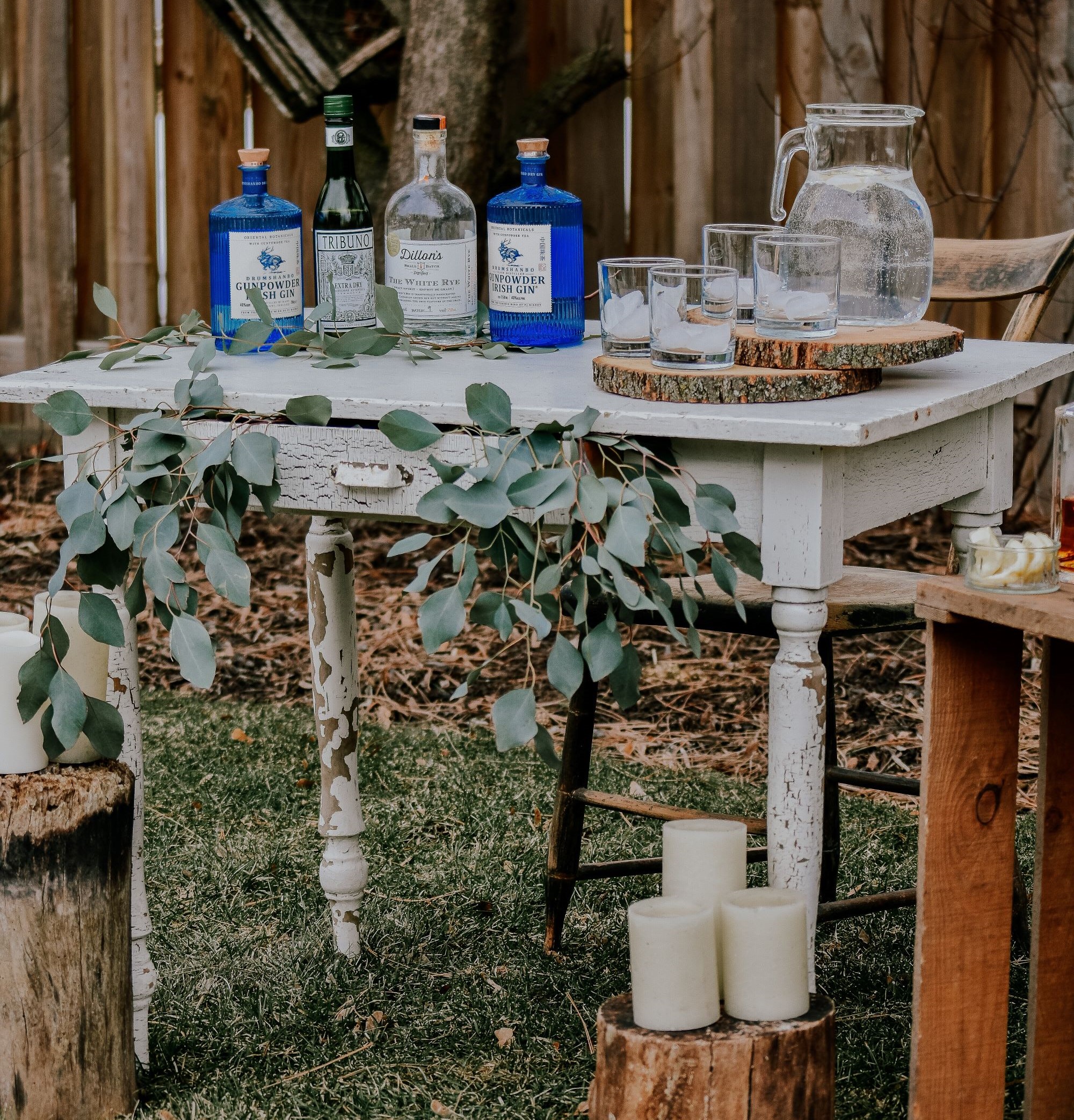 A party bar made from a small white desk with candles and water for a DIY wedding